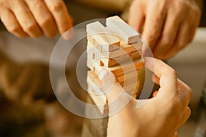 Close up of senior man`s hands doing his wooden constructor at home - concept of home studying