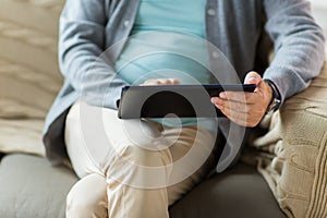 Close up of senior man with tablet pc on sofa
