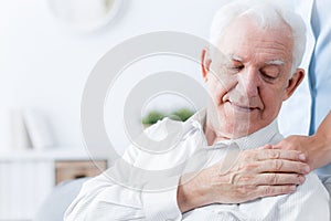 Close-up of senior man touching hand of friendly caregiver