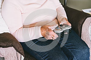 Close up senior, mature woman hands using wireless controller, joystick gamepad playing video games at home. Fun on