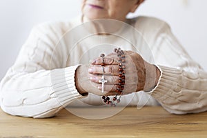 Close-up on senior person;s hands with rosary and cros