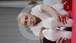 Close-up of Senior woman doing stretching exercise at home. Vertical format video