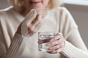 Close up of senior woman feeling unwell taking pill photo