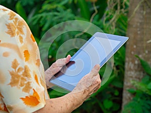 Close-up of senior woman hands holding a tablet. Concept of aged people and technology
