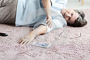 Close-up of senior woman with heart attack and smartphone on the