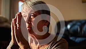 Close Up Of Senior Woman At Home Praying Or Meditating With Hands Together