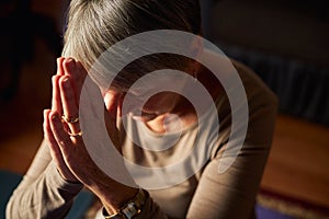 Close Up Of Senior Woman At Home Praying Or Meditating With Hands Together