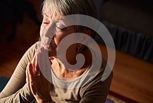 Close Up Of Senior Woman At Home Praying Or Meditating With Hands Together