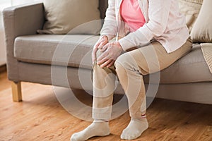 Close up of senior woman with pain in leg at home