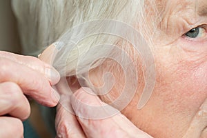Close Up Of Senior Woman Putting In Hearing Aid
