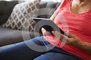 Close Up Of Senior Woman On Sofa Using Digital Tablet