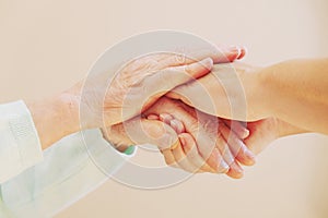 Close up of senior woman and young woman holding hands. Care and support concept