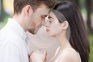 Close up of sensual couple holding hands touching noses