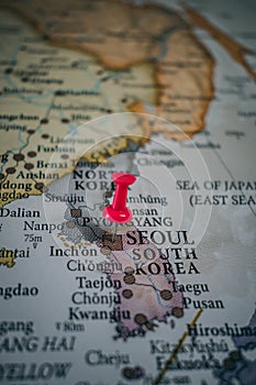 Close up of Seoul pin pointed on the world map with a pink pushpin