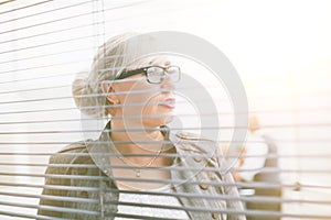 close up. serious business woman looking through office window