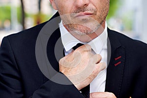 Close up serious businessman adjusting knot on tie