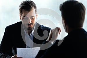 Close up serious businessman reading cv new job candidate.