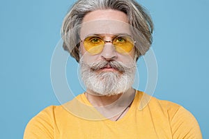 Close up of serious elderly gray-haired mustache bearded man in casual yellow t-shirt, eyeglasses posing isolated on
