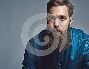 Close up on serious man in blue shirt and beard