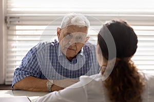 Close up serious old man listening to doctor at meeting