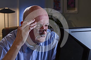 Close up of serious older man using home computer, horizontal