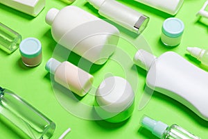 Close-up set of diffrent sized bottles and jars for cosmetic products on green backgound. Face and body care concept with copy