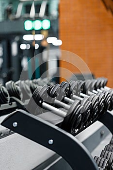 Close up set of dumbbells on black metal steel on rack in sports fitness center.