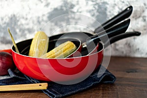 close up of a set of red pans with vegetables