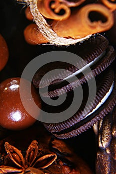 Close-up set of round crunchy chocolate cookies with coffee beans, sticks of cinnamon, anise star on a black background, macro, se