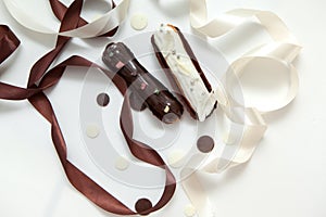 Close-up of a set of two eclairs with different fillings and design isolate on a white surface decorated with chocolate drops,