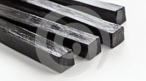 A close-up of several black, rectangular licorice sticks arranged on a white surface