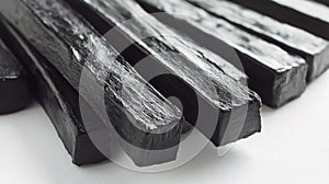 A close-up of several black, rectangular licorice sticks arranged on a white surface