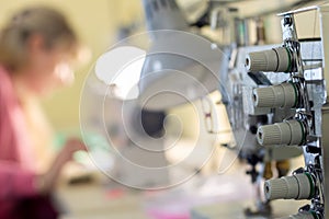 Close-up of sewing equipment with threads and a worker in the background