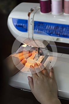 Close up hand sewing fabric with white sewing machine and thread