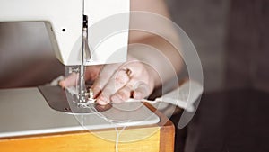 Close up of sewing machine with women's hands on table. Woman stitching curtain, using sewing machine.