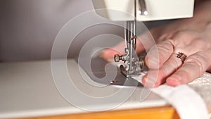 Close up of sewing machine with women`s hands on table. Woman stitching curtain, using sewing machine.