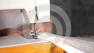 Close up of sewing machine with women's hands on table. Woman stitching curtain, using sewing machine.