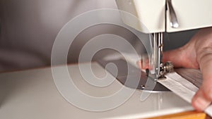 Close up of sewing machine with women's hands on table. Woman stitching curtain, using sewing machine.