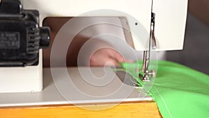 Close up of sewing machine with women`s hands on table. Woman stitching curtain, using sewing machine.