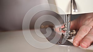 Close up of sewing machine with women`s hands on table. Woman stitching curtain, using sewing machine.