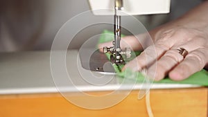 Close up of sewing machine with women`s hands on table. Woman stitching curtain, using sewing machine.