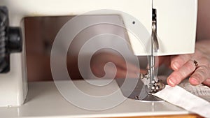 Close up of sewing machine with women`s hands on table. Woman stitching curtain, using sewing machine.