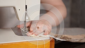 Close up of sewing machine with women`s hands on table. Woman stitching curtain, using sewing machine.