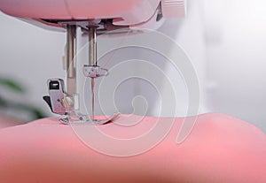 Close up of sewing machine working with pink fabric, stitch new clothing