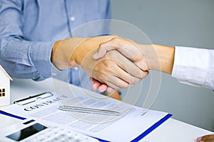 Close up of shaking hands with customer and real estate broker after signing a contract in home office