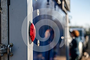 Close-up, shallow focus of a rear light seen attached to a horse trailer and box.