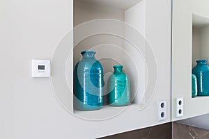 Close-up shelf detail of a bathroom with 2 green and blue vases.