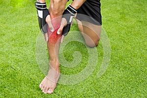 Close up on shin Injury. The man use hands hold on his shin while running in the park. space for text or design. highlight on