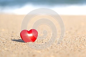 Close-up of A Shining Red Heart on Beach Sand
