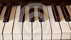 Close-up of shiny black and white old piano keys with golden brass edge reflection with shallow depth of field.